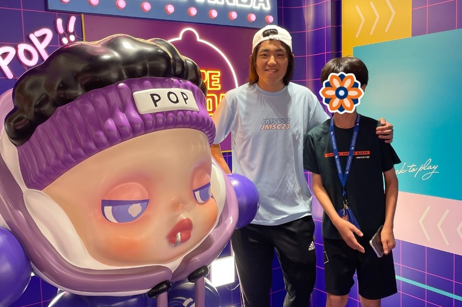 KKOOM mentor and student enjoy a field trip experience in Seoul, standing next to a colorful POP art statue. The child’s face is covered for privacy.